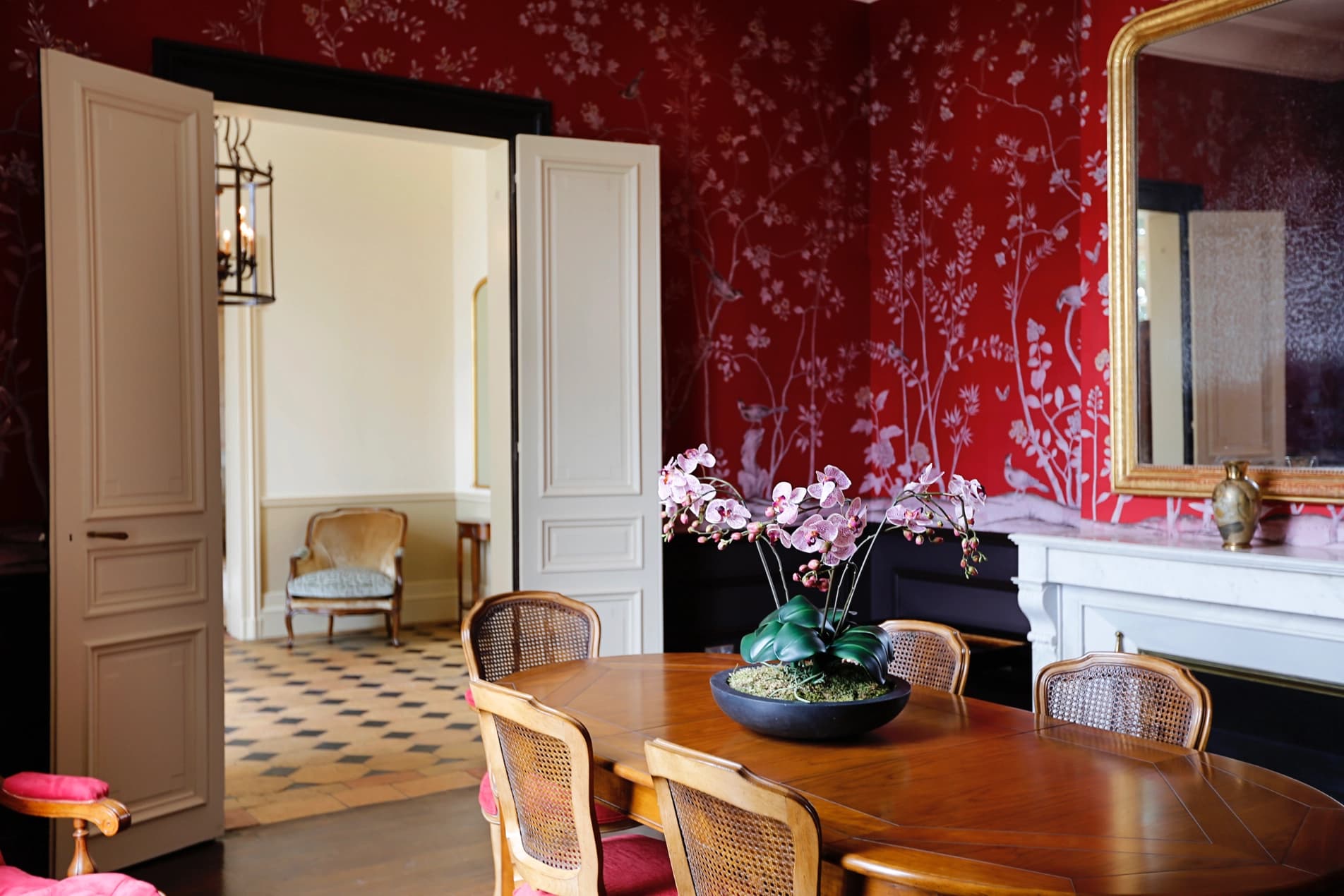 Dining room with red chinoiserie wallpaper and wooden table